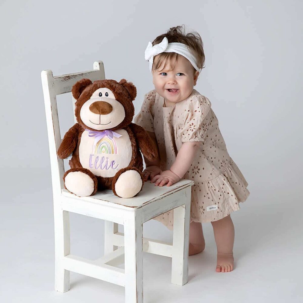 Liten jente med teddybjørn med brodert navn