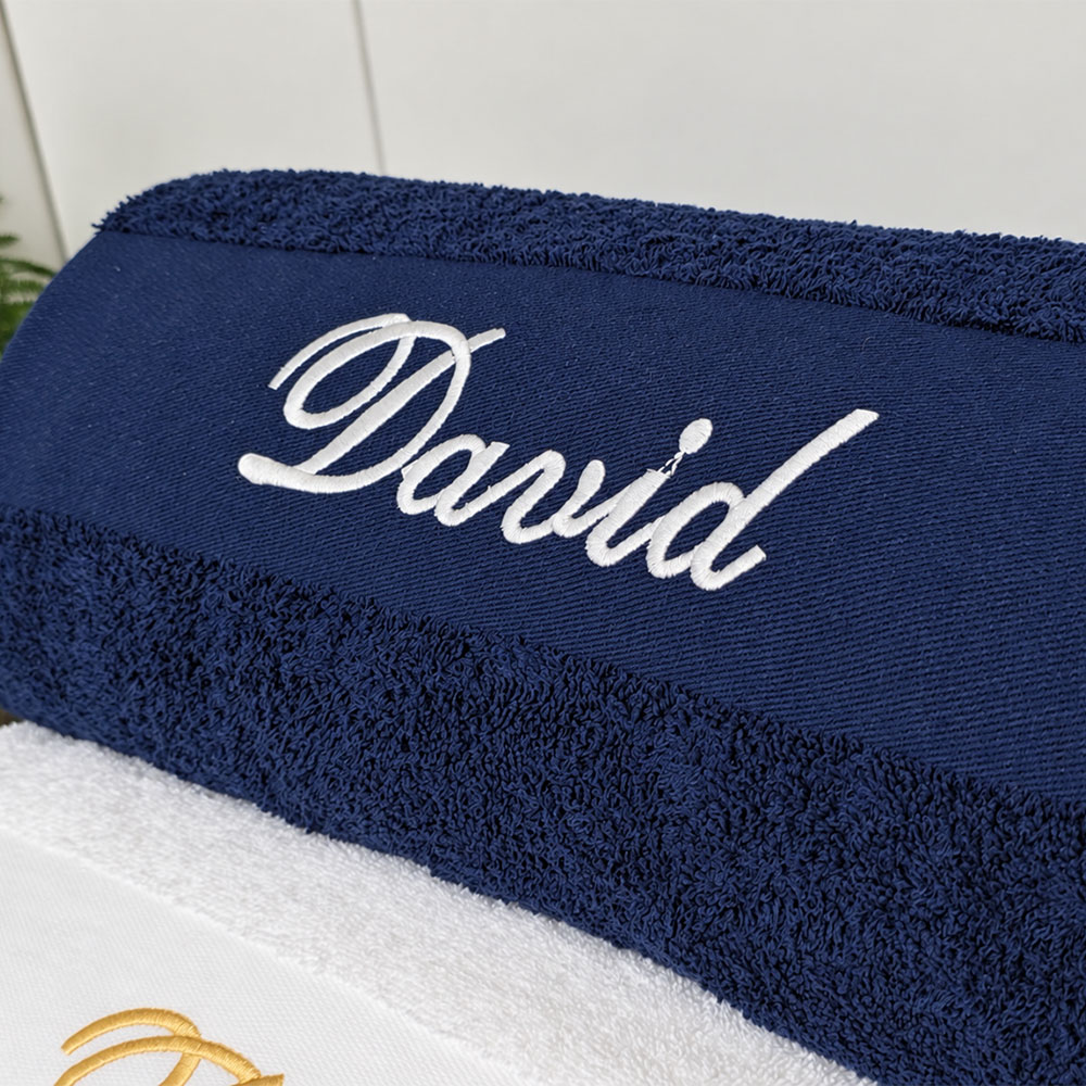 Marineblått håndkle med navn i bruk på badet