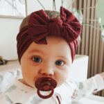Baby med burgunder hårbånd og smokk